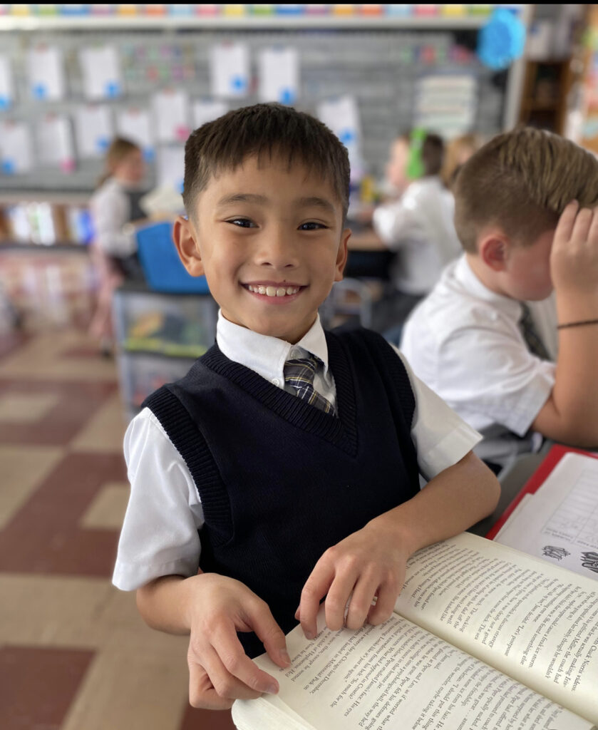 Student in a classroom reading from an open book