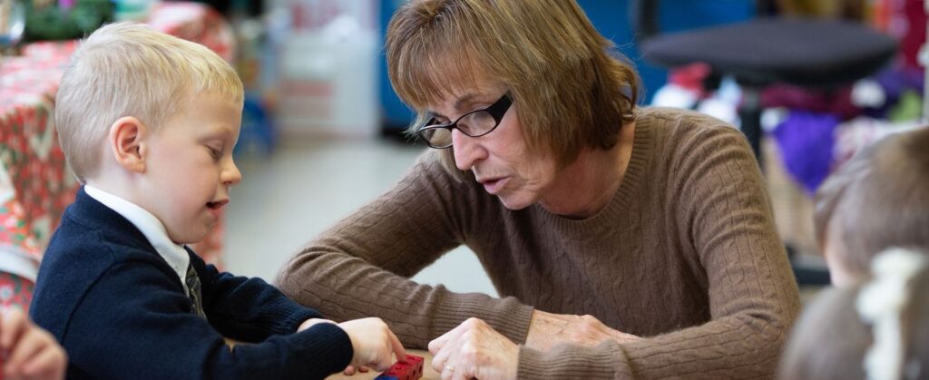 Teacher working with a young student using blocks in a classroom